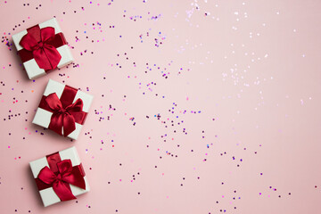 Gift box with red ribbon over the pink background with copy space.