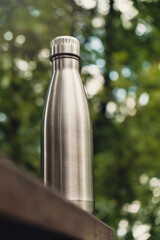 Water bottle. Reusable steel thermo water bottle on wooden bench isometric concept. Sustainable...