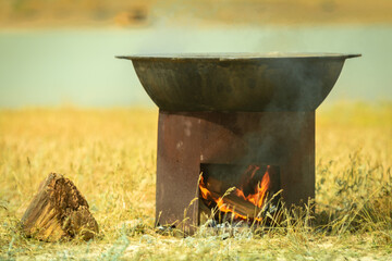 Field kitchen. A large cauldron is heated on a brazier. Cooking pilaf in the steppe of central asia.