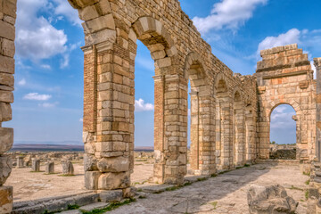 Fototapeta na wymiar The brick and stone arched exterior wall of the basilica at restored Roman ruins at Volubilis, Morocco.