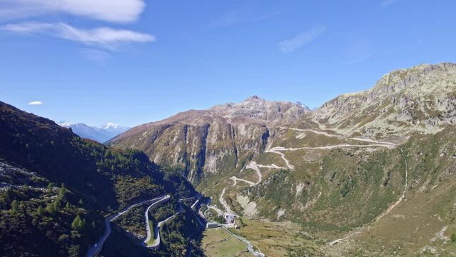 Aerial view of famous Swiss mountain pass Furkapass at 2436 meters above sea level with mountain village Gletsch on a sunny late summer day. Movie shot September 12th, 2022, Furka Pass, Switzerland.