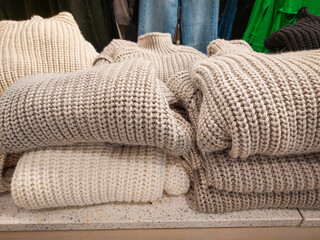 Stack folded sweaters in the clothing store. Knitted jumpers for cold fall and winter season