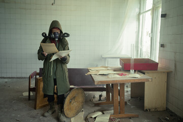 Disaster survivor in a post apocalyptic setting, she is wearing a gas mask and reading document. Environmental pollution, ecological disaster, nuclear war, post apocalypse