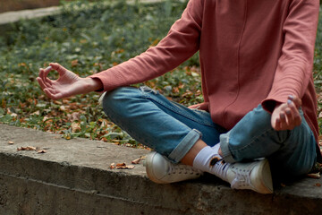 A woman in Casual clothes does yoga in an old park