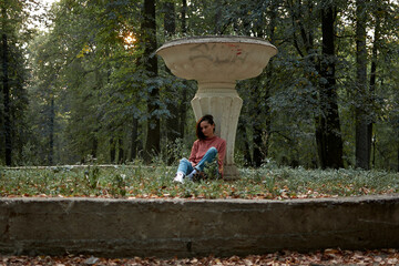 A woman in Casual clothes does yoga in an old park