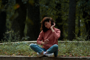 A woman in Casual clothes does yoga in an old park