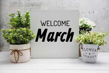 Welcome March text message with artificial plant decoration on wooden background