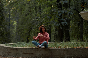 A woman in Casual clothes does yoga in an old park