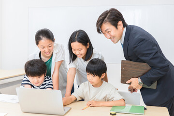 パソコンゲームで遊ぶ小学生の子供達と先生（学校・塾）
