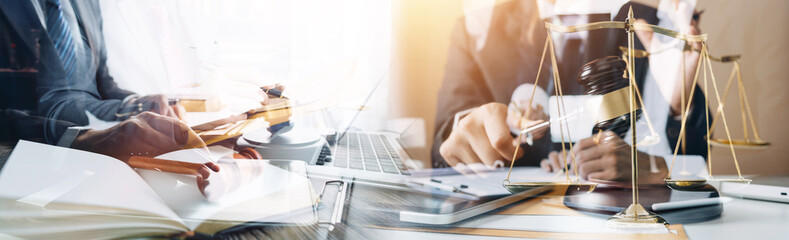 Business and lawyers discussing contract papers with brass scale on desk in office. Law, legal services, advice, justice and law concept picture with film grain effect