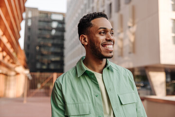 Smiling young male smiling broadly looking away spending time outdoors. Brunette guy with stubble...