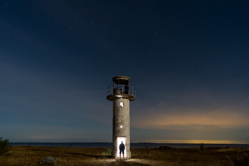 Night scene, a man enters an old lighthouse glowing inside.