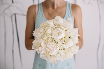 Very nice young woman holding big and beautiful mono wedding bouquet of fresh white Peony flowers,...