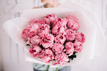 Very nice young woman holding huge and beautiful mono bouquet of fresh pink peonies cropped photo,...