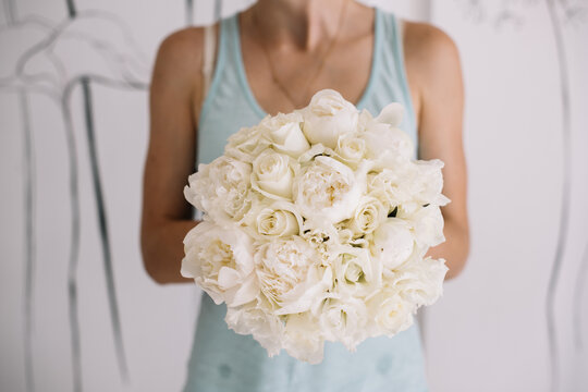 Very nice young woman holding big and beautiful mono wedding bouquet of fresh white Peony flowers, cropped photo, bouquet close up