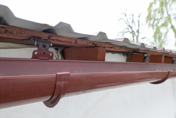 Gutter system for a metal roof. Holder gutter drainage system on the roof. © filins