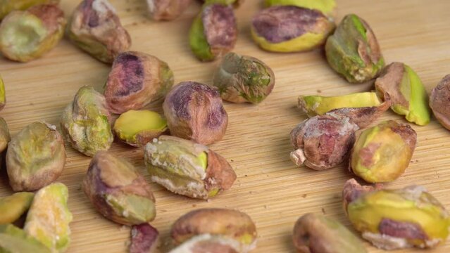 Pistachios without shells top view rotation. Pistachio nuts. Whole nut kernels. Pistachios kernels on wooden board. Roasted nuts with salt, nutrien snacks.