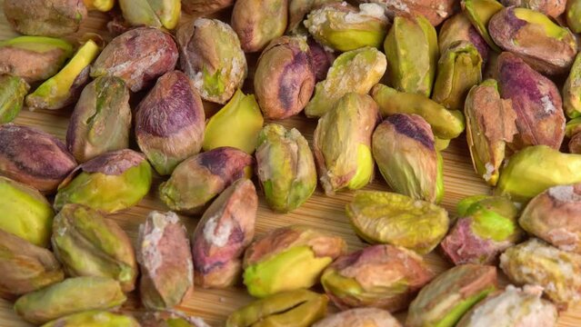 Pistachios without shells top view rotation. Pistachio nuts. Whole nut kernels. Pistachios kernels on wooden board. Roasted nuts with salt, nutrien snacks.