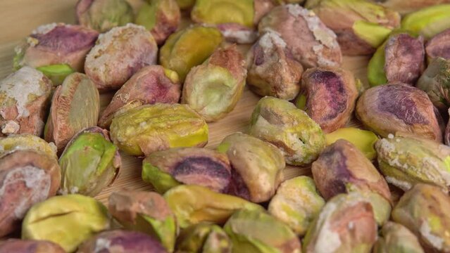 Pistachios without shells top view rotation. Pistachio nuts. Whole nut kernels. Pistachios kernels on wooden board. Roasted nuts with salt, nutrien snacks. High quality 4k footage