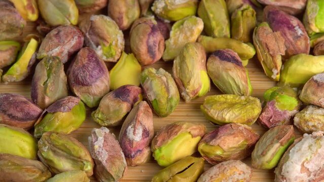 Pistachios without shells top view rotation. Pistachio nuts. Whole nut kernels. Pistachios kernels on wooden board. Roasted nuts with salt, nutrien snacks. High quality 4k footage
