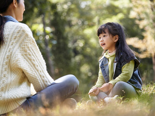 young asian mother having a pleasant conversation with daughter outdoors