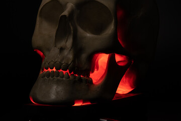 A skull with an illuminated jaw in red light. An ominous look that inspires fear