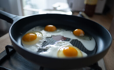 Scrambled eggs in black frying pan on the fire. Morning start with good breakfast