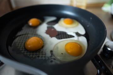 Scrambled eggs in black frying pan on the fire. Morning start with good breakfast