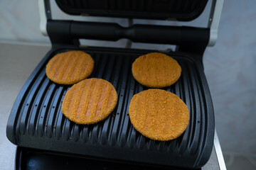 Round fish cutlets in breading, fried on an electric grill