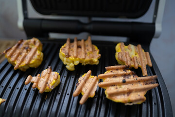 Cauliflower fried in an egg on an electric grill