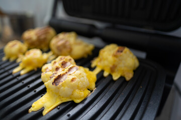 Cauliflower fried in an egg on an electric grill