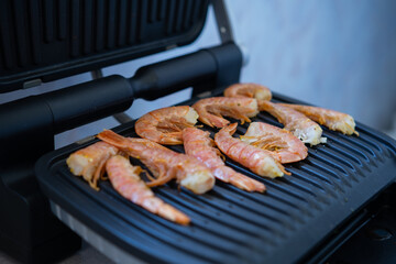 Cooking fresh large shrimp on an electric grill. Picnic on the balcony