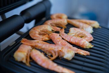 Cooking fresh large shrimp on an electric grill. Picnic on the balcony