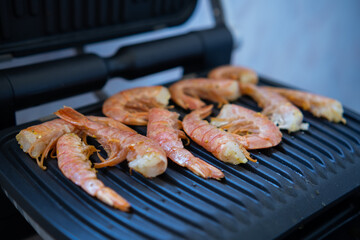 Cooking fresh large shrimp on an electric grill. Picnic on the balcony