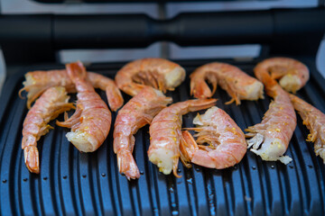 Cooking fresh large shrimp on an electric grill. Picnic on the balcony
