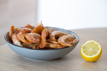 Grilled shrimp in a plate in the kitchen. Nearby, a lemon lies on the table for extra flavor