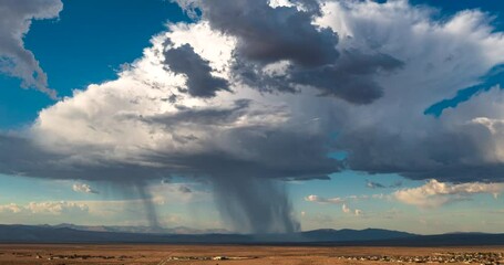 Rain clouds in a torrential downpour over the Mojave Desert with California City in the foreground - aerial hyper lapse - Powered by Adobe