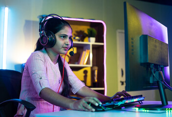 gamer seriously playing live video game on computer with headphones at home - concept of live streamer, vlogger and tournament. © WESTOCK