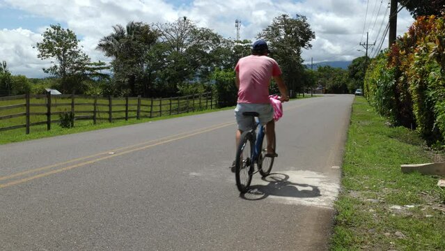 Car and a bicycle passing by on a road in the countryside of Sierpe, Costa Rica