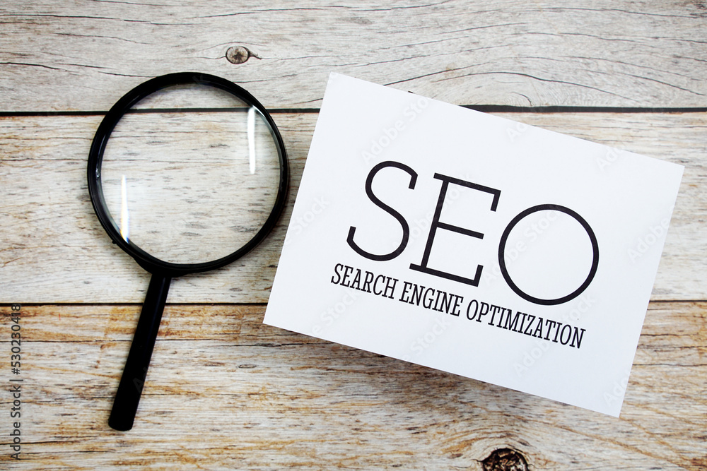 Aufkleber seo search engine optimization text message with magnifying glass on wooden background
