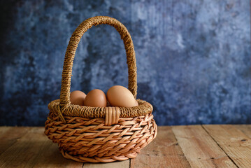 Fototapeta na wymiar Farm fresh eggs in a wicker basket. Blue background.