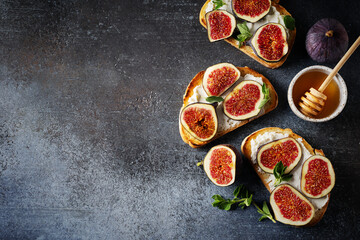 Fig bruschetta, bread and cream cheese and fruit on dark background