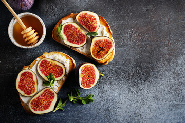 Fig bruschetta, bread and cream cheese and fruit on dark background