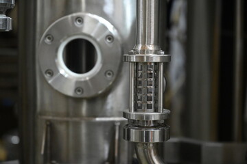 Industrial interior of modern craft brewery with chrome cylindrical metal beer tanks.