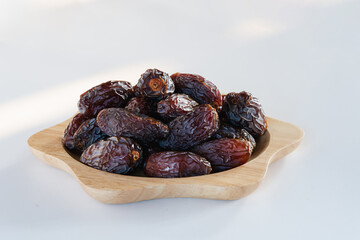 Medjool dates in a wooden container on a white background. It is a fruit that Muslims eat during the fasting month.