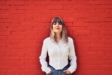Pretty, blonde, young woman having fun making different expressions in front of a red background wall. Concept various expressions. Laughter, sadness, tired, angry, hate.