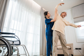 Rehabilitation of disabled people. Old senior man enjoys training with physiotherapist for outstretched arms at home, Asian physical therapist patient help elderly exercising arm stretch