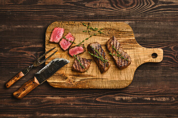 Overhead view of grilled beef steak on shabby cutting board