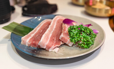 Raw pork belly on a plate and raw beef fat piled in volcano shape