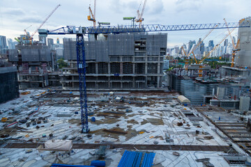 Aerial view of a large construction of a residential area with many multi-storey buildings under construction, a lot of tower cranes, workers, construction equipment at sunset